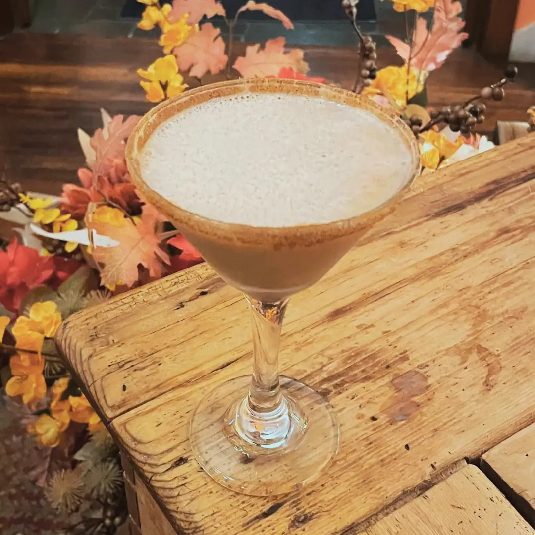 A cocktail in a Martini glass sitting on a wooden table