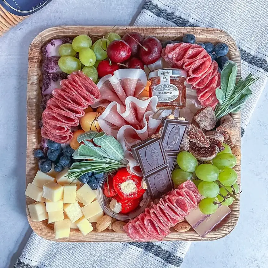 A beautiful charcuterie board with meats, cheeses and fruites.